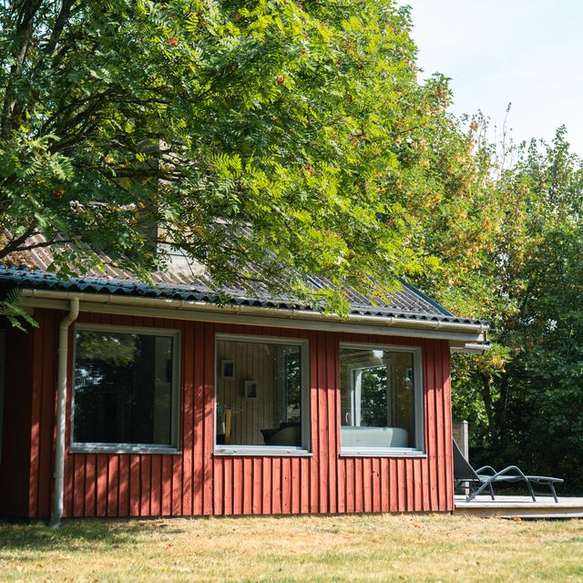 Sommerhuset set fra siden med terrasse og liggestol